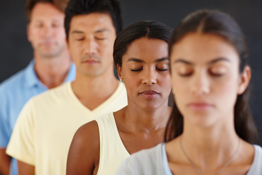 Four individuals stand in line, eyes gently closed, embodying a calm and focused aura. This serene moment captures the essence of Sample Post #2.